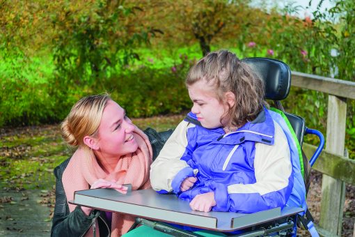 disabled girl in a wheelchair together with a care assistant