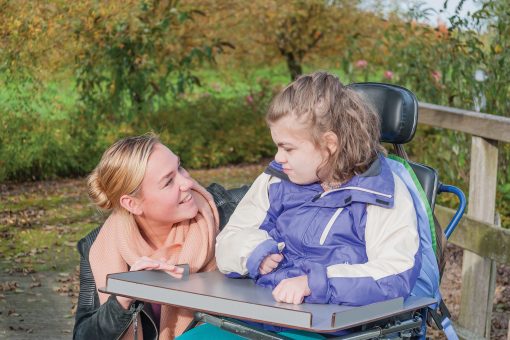 Disabled girl in a wheelchair together with a care assistant