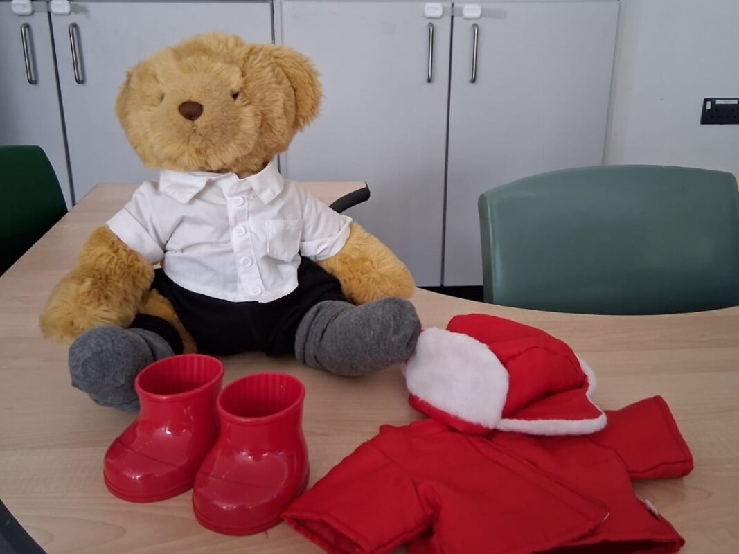 Teddy bear seated next to red clothing.
